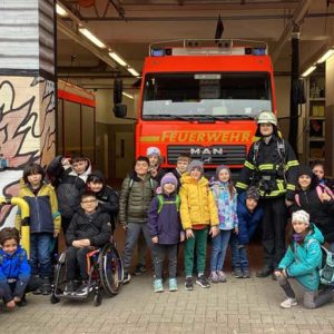 Gruppenbild: Schulklasse vor einem Feuerwehrauto in der Feuerwehr-Garage