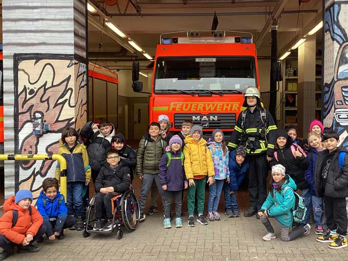 Gruppenbild: Schulklasse vor einem Feuerwehrauto in der Feuerwehr-Garage