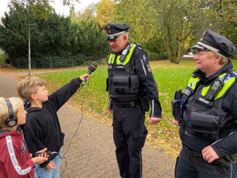 Zwei Jungs interviewen einen Polizisten und eine Polizistin